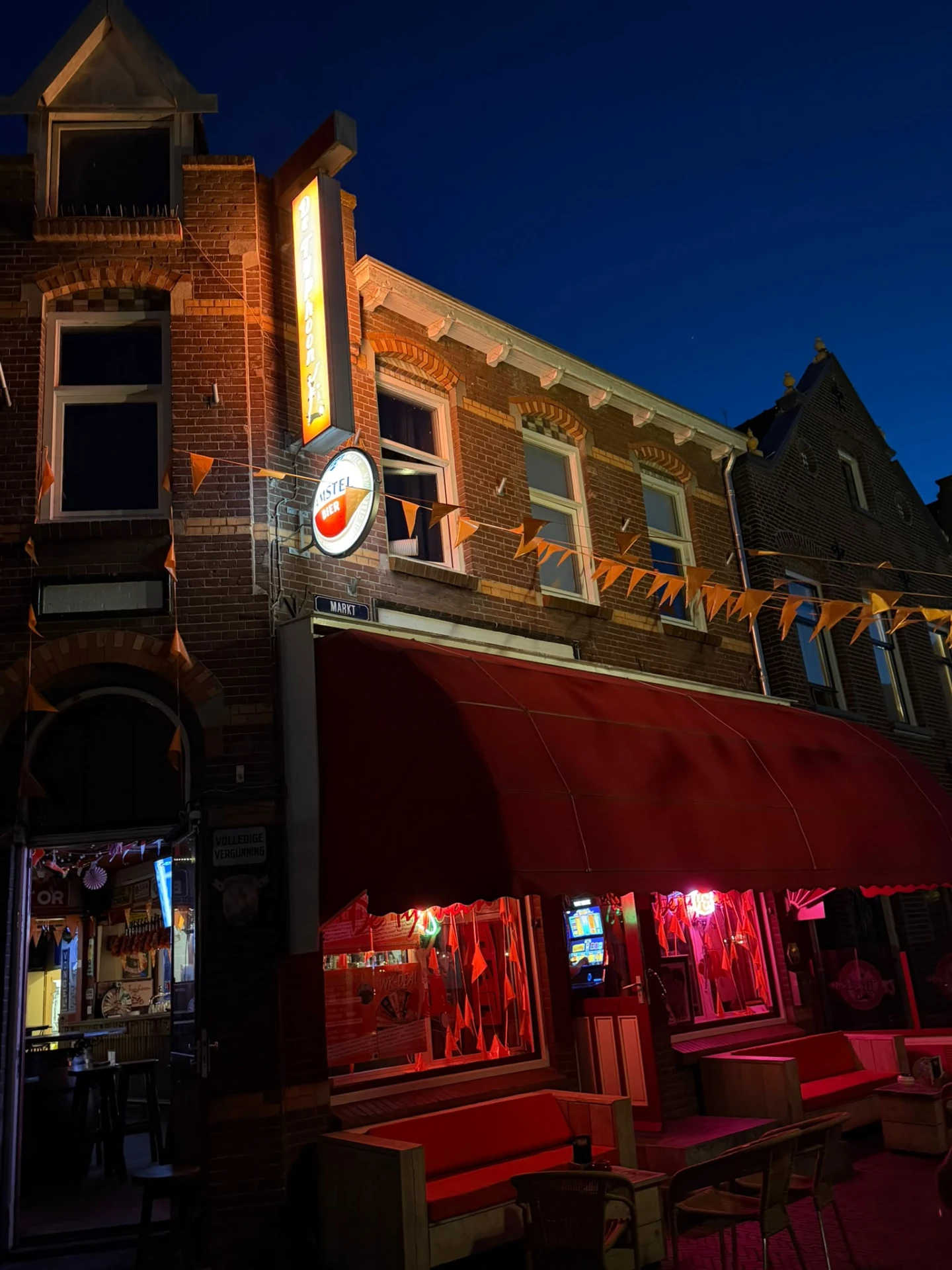 Het verlichte terras en de luifel van Café De Typhoon 's avonds