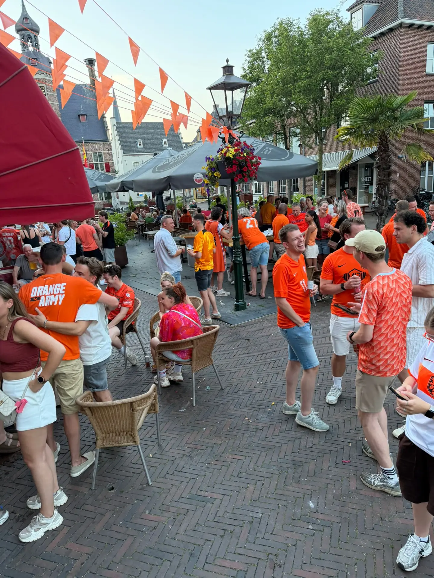 Gasten in het oranje vieren feest op het terras van De Typhoon