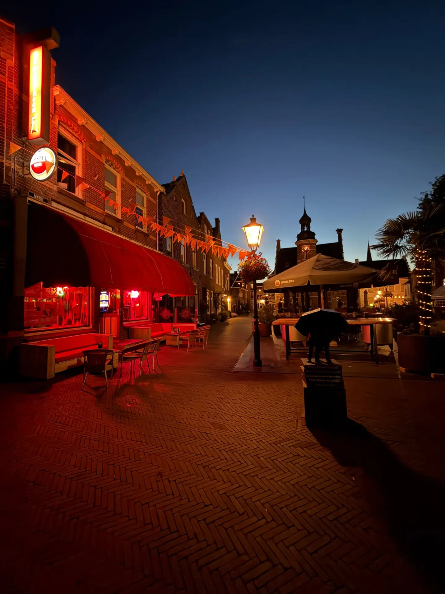 Avondfoto van Café De Typhoon aan de Markt met de rode luifel verlicht